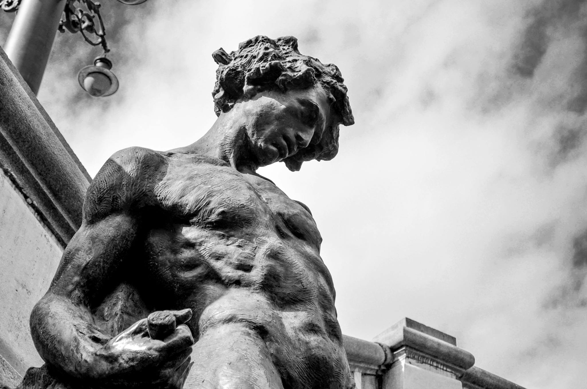 Low-angle shot of a powerful monochrome statue against a cloudy sky.